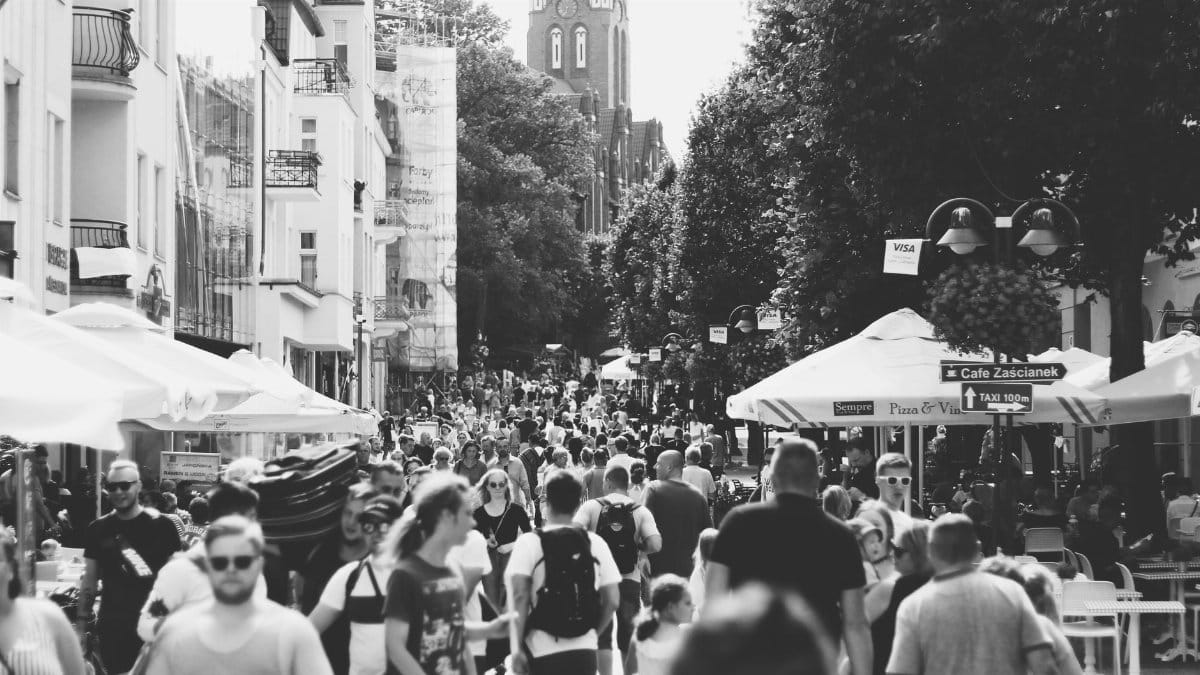 A black and white photo capturing a busy street filled with people in Sopot, Poland during the day.