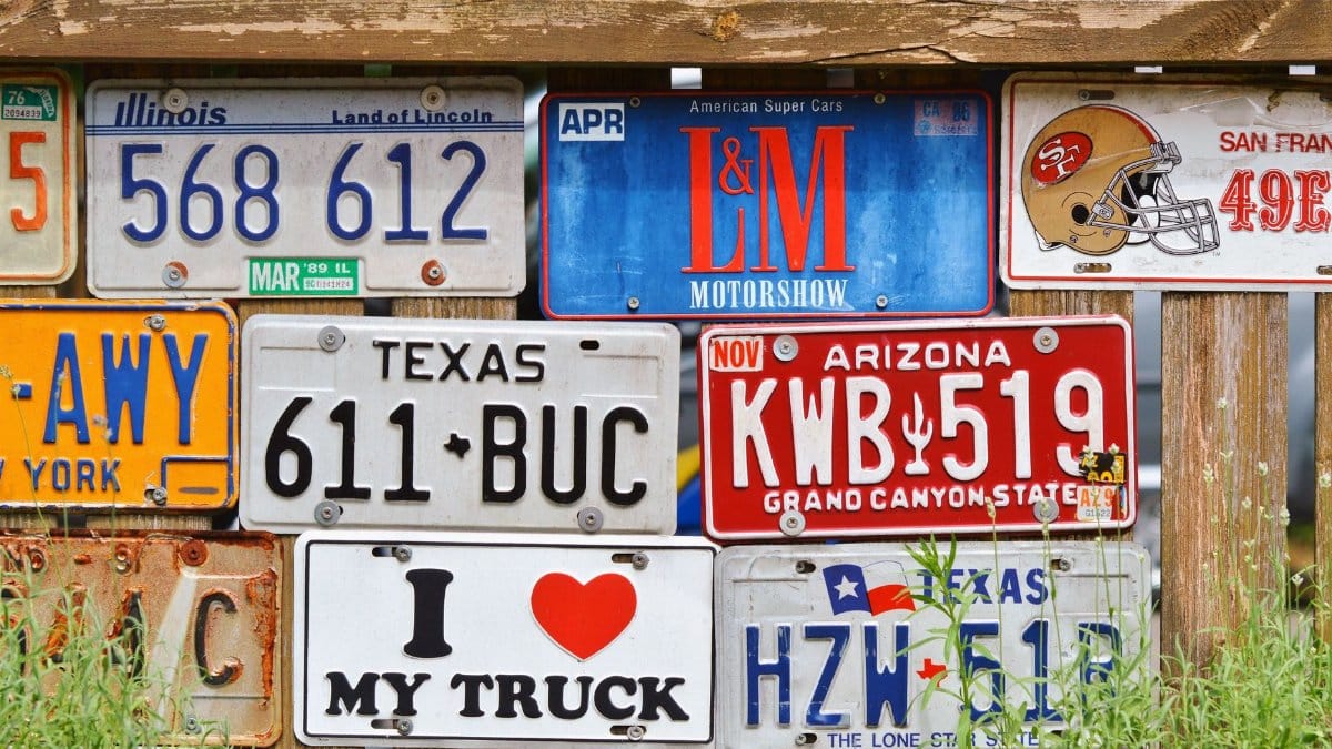 Decorative display of vintage American license plates on a rustic wooden fence.