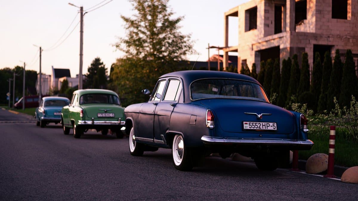 Classic cars parked alongside a quiet urban street during sunset, capturing a nostalgic vibe.