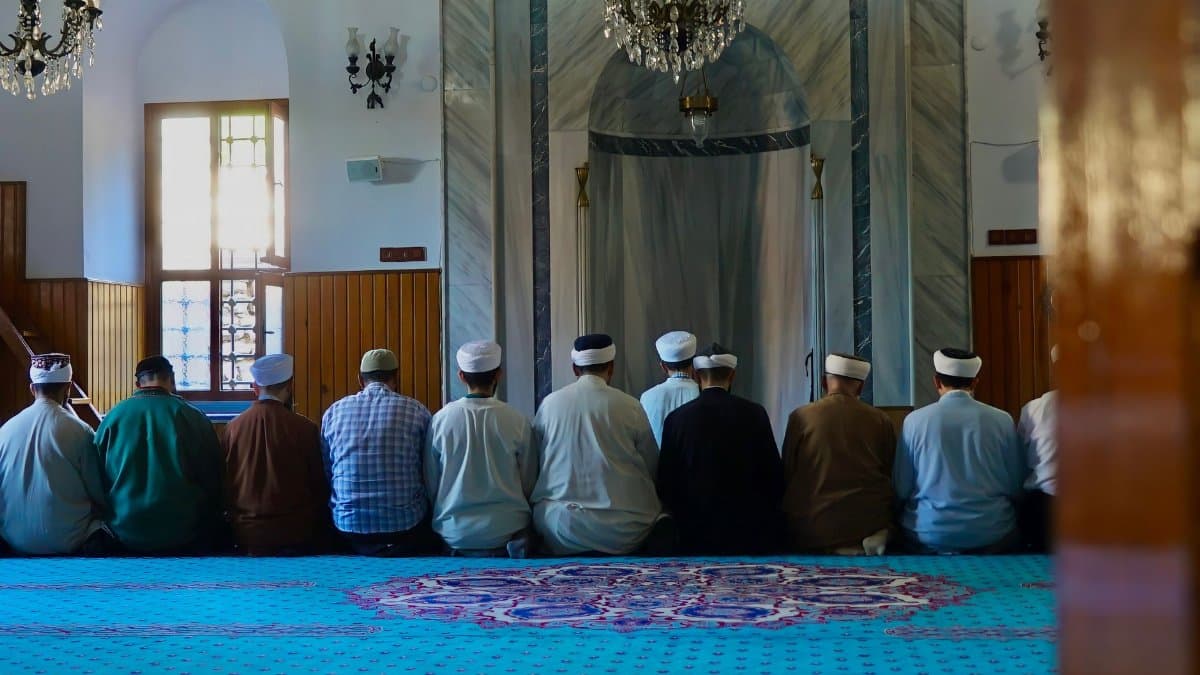 Group of men praying inside a traditional mosque in Istanbul, showcasing Islamic architecture.