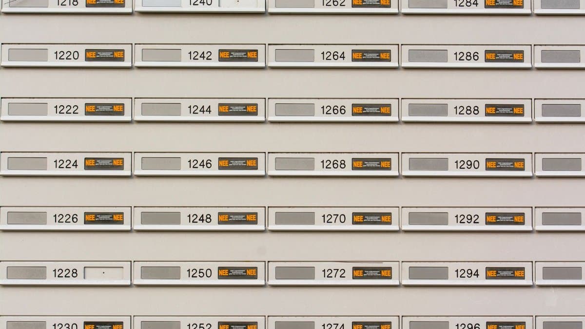 Row of modern mailboxes with numbers in an urban setting, featuring a pattern.