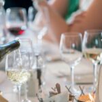 A sophisticated dinner setting with a focus on wine pouring creates a luxurious dining ambiance.