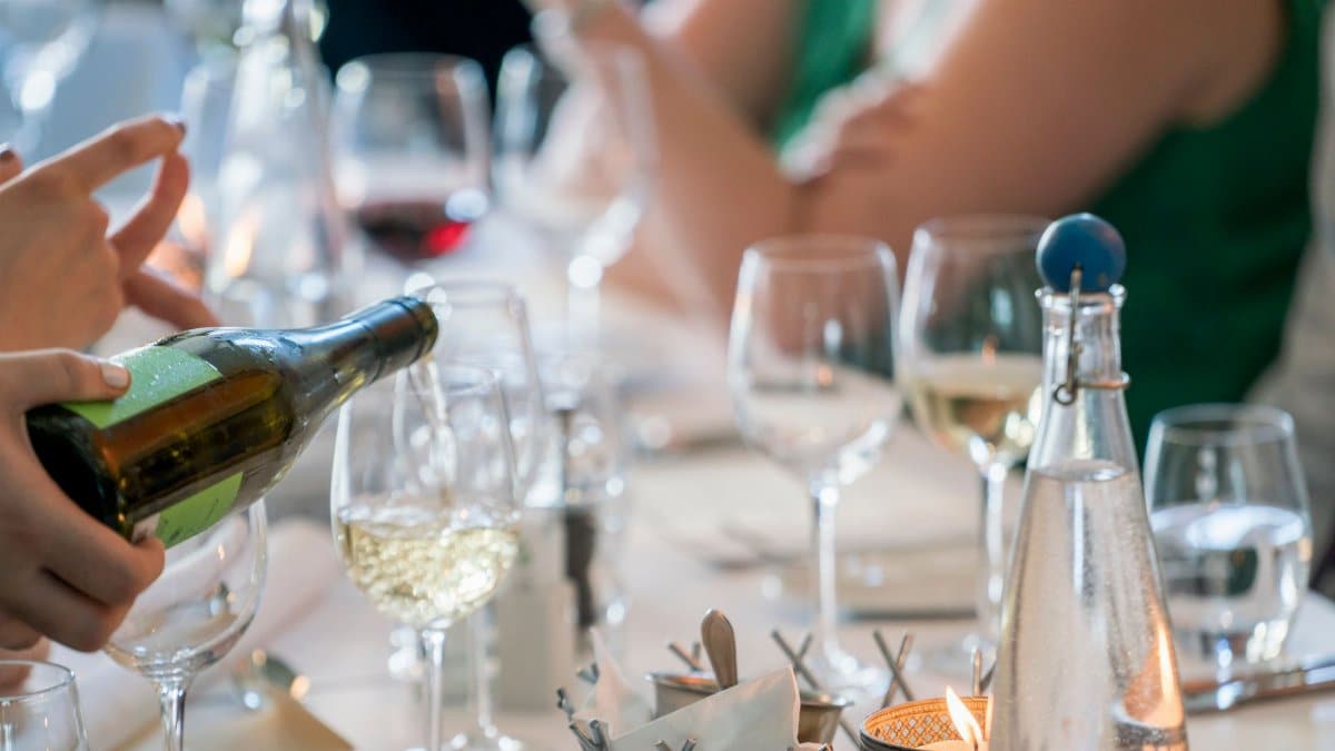 A sophisticated dinner setting with a focus on wine pouring creates a luxurious dining ambiance.