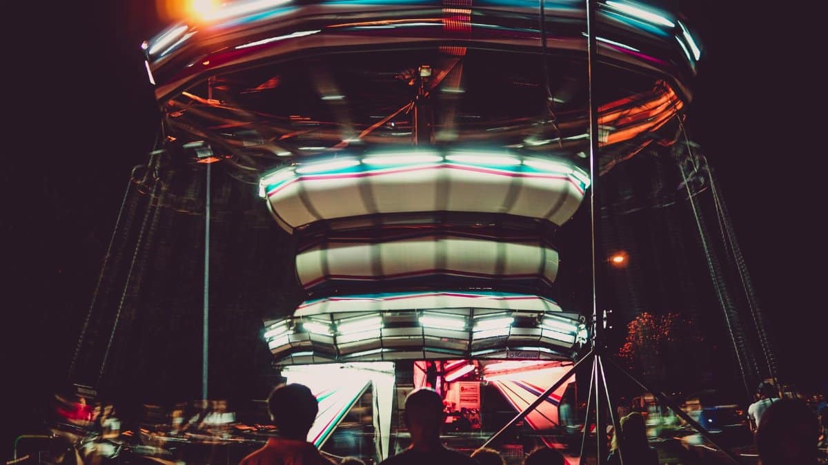 A colorful and dynamic carousel ride at night with motion blur and vibrant lights.