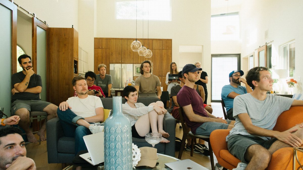 A group of adults attentively listening during a casual meeting in a modern living room.