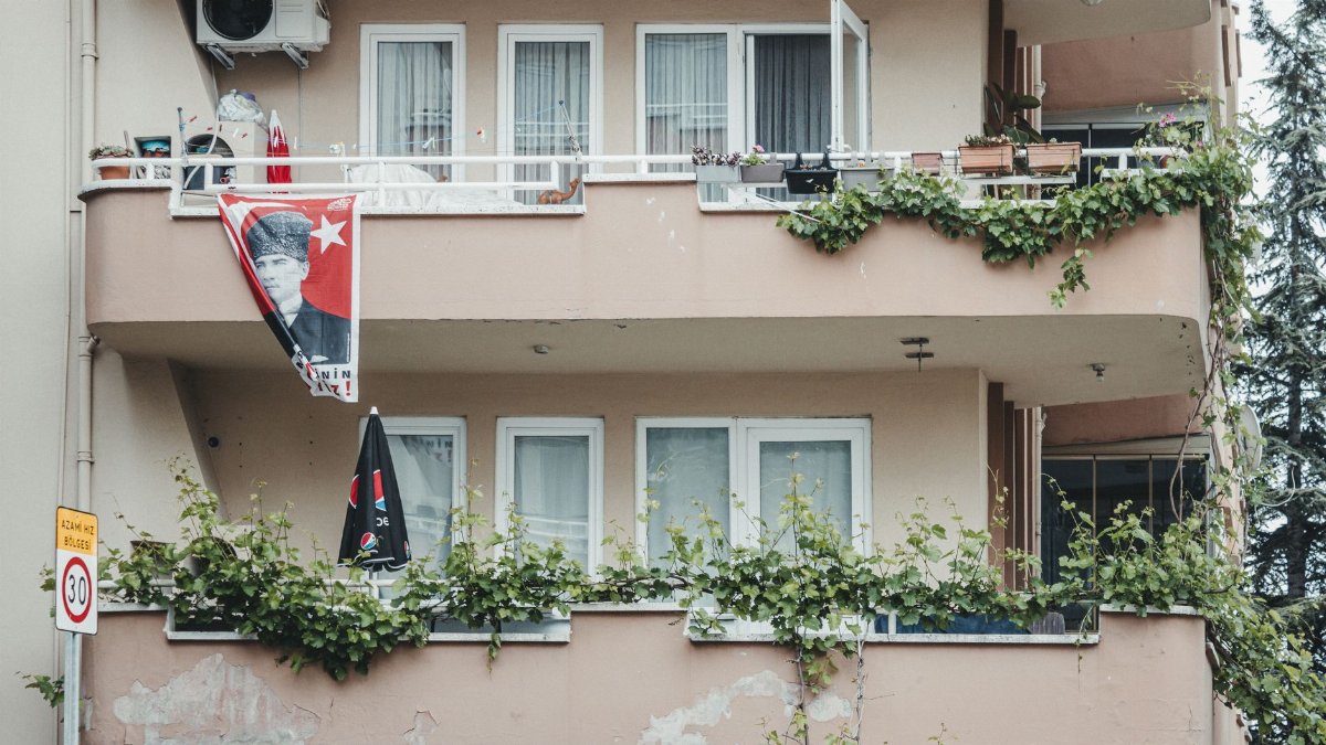 Apartment balconies adorned with greenery and a flag on display, urban setting.