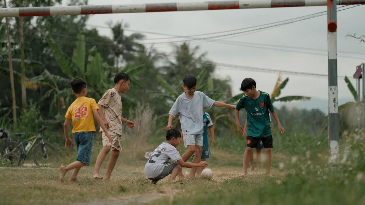 Group of children playing soccer outdoors in a rural setting