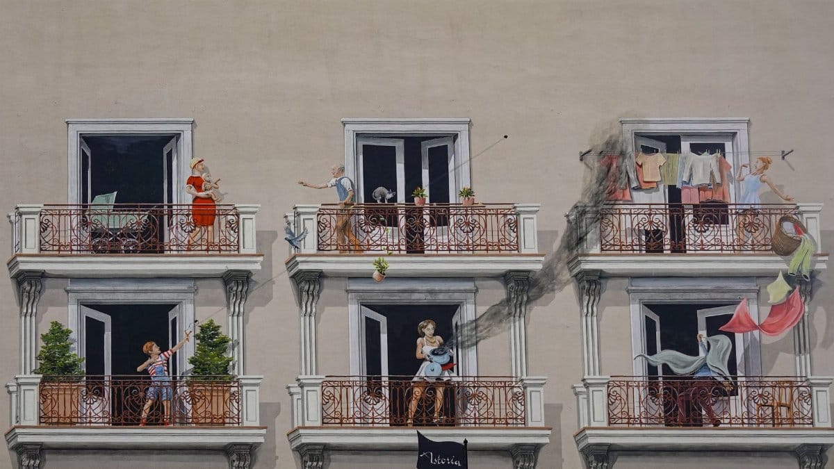 Colorful urban mural depicting various people on balconies, adding life to a building exterior.