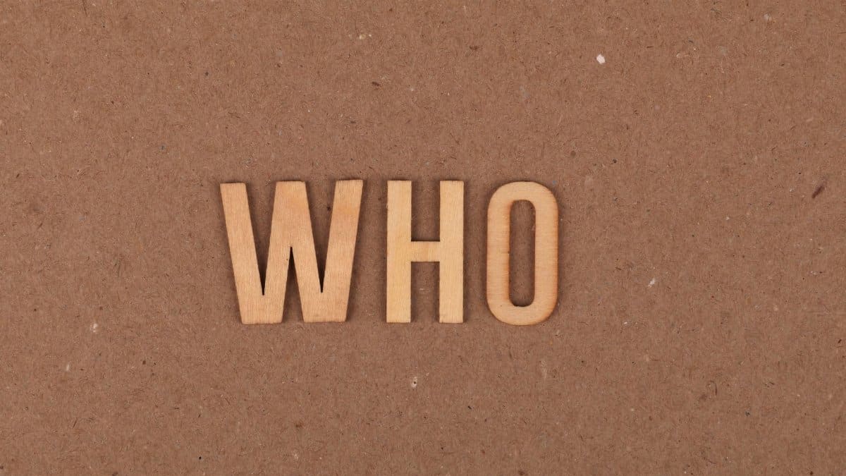 Wooden letters forming the word WHO on a textured cardboard surface.