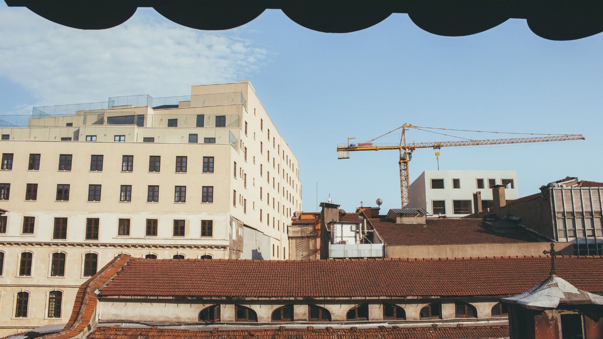 City skyline with buildings and a crane against a clear sky.