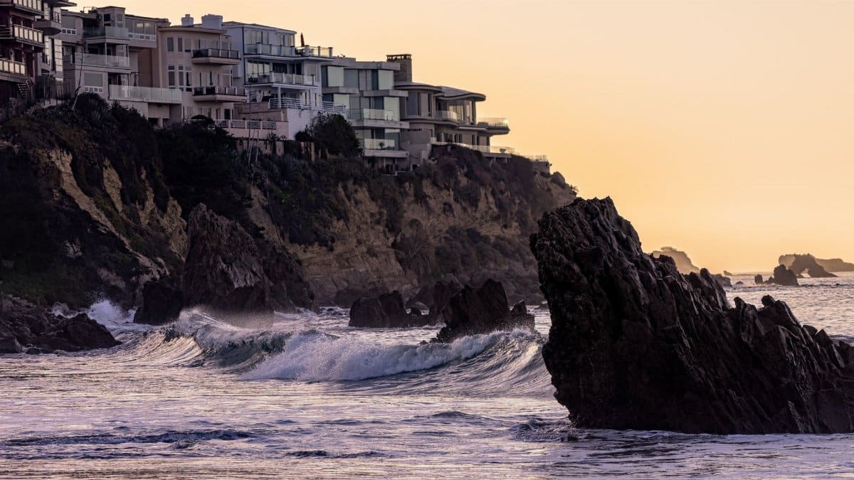 Dramatic ocean waves crash against cliffs at sunset in Newport Beach, California.