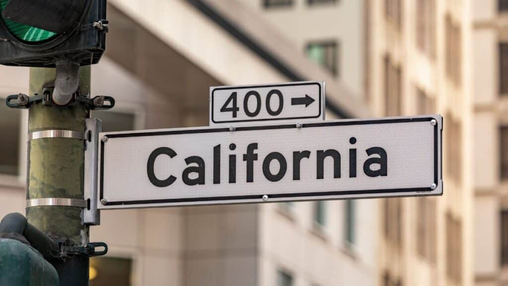 Street sign for California with traffic light in cityscape. Urban navigation and signage theme.