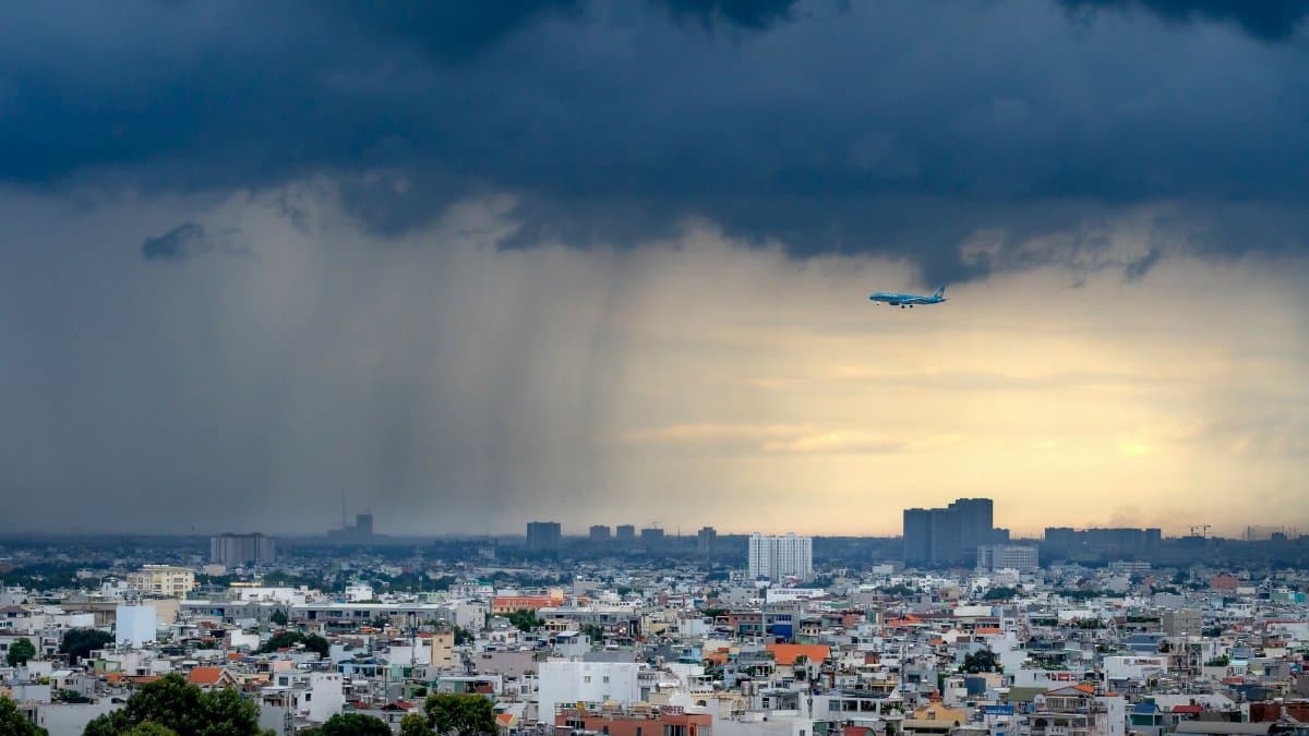 Dramatic view of a plane flying over a city during a storm with heavy clouds and rain.