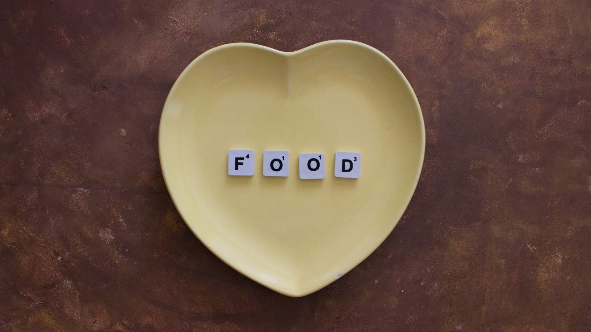 Creative arrangement of Scrabble tiles spelling 'FOOD' on a heart-shaped plate, perfect for culinary themes.