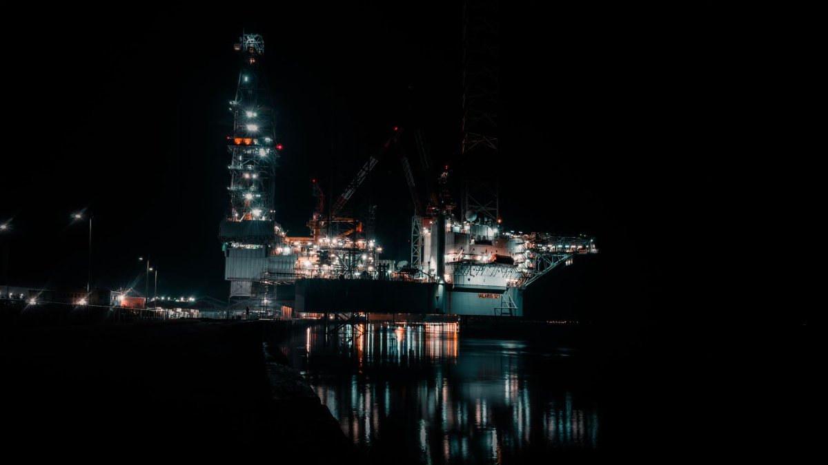 A dramatic offshore oil rig brilliantly lit against the nighttime sky.