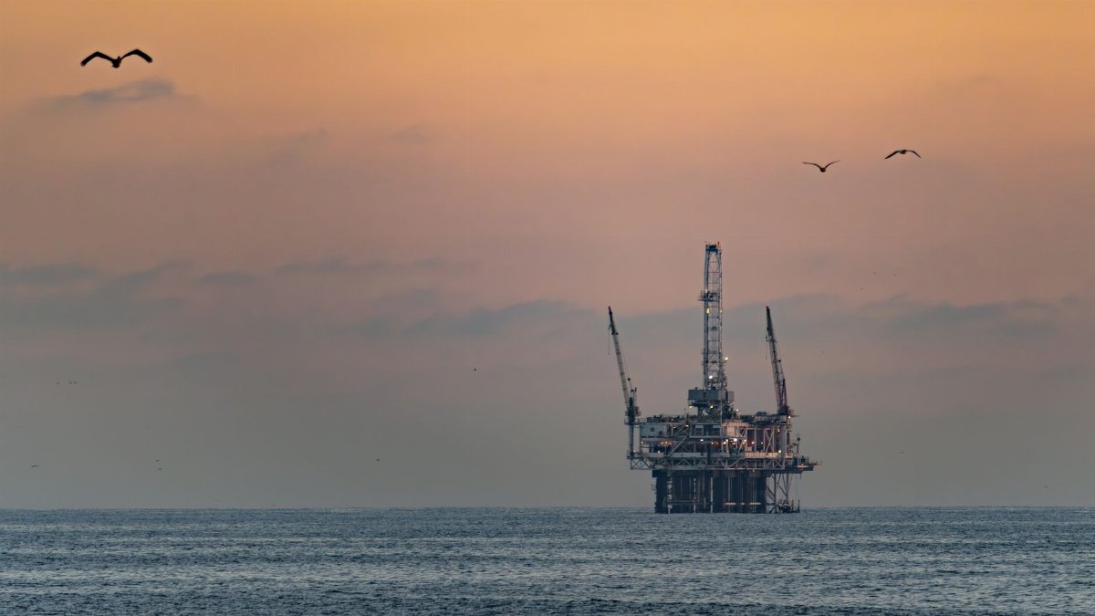 Oil platform silhouetted against a vibrant sunset in Huntington Beach, California.