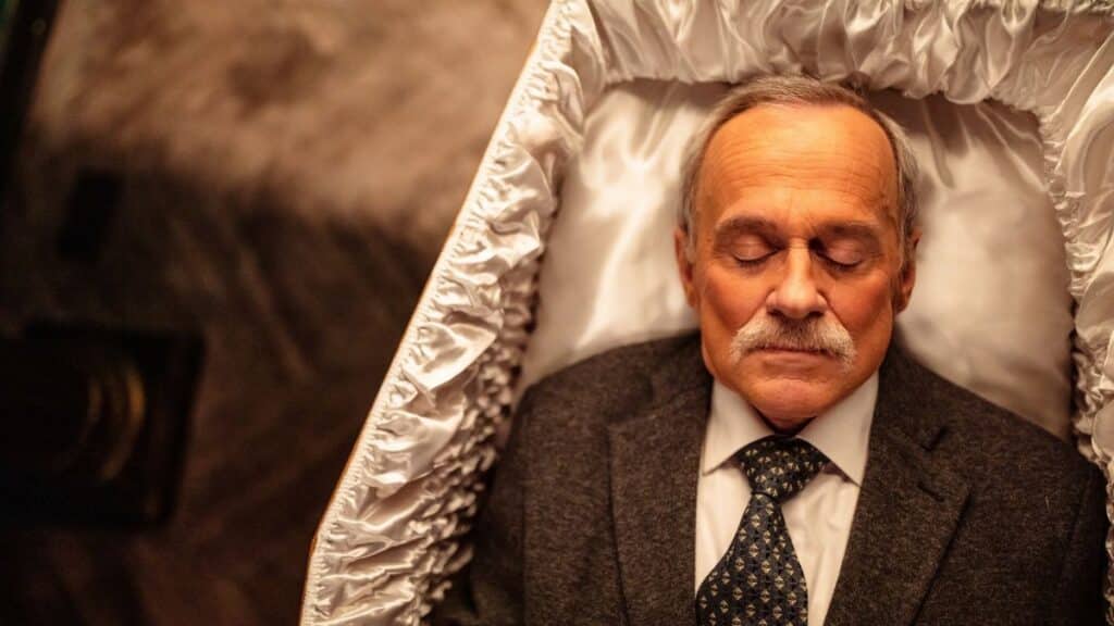 Top view of a senior man in a coffin, dressed in a suit, symbolizing serenity.
