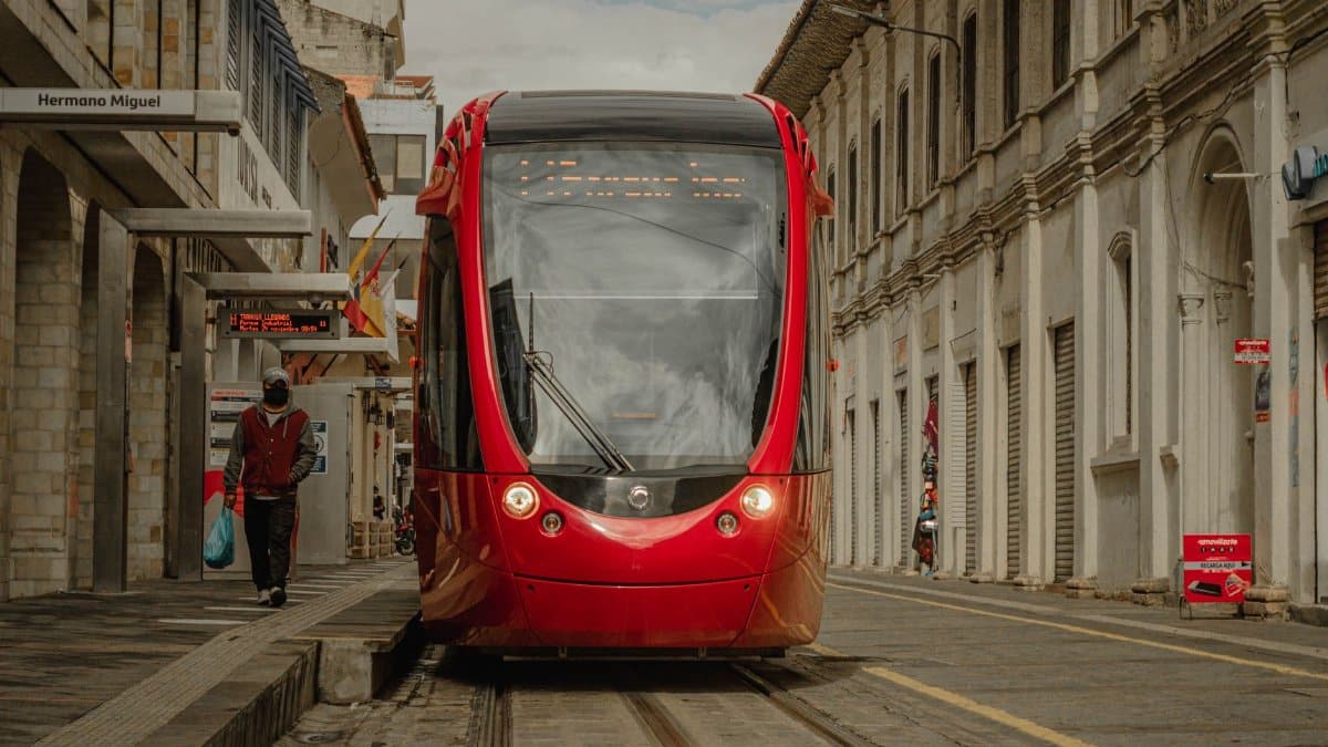 A vibrant red tram navigates the historical streets of Cuenca, Ecuador.