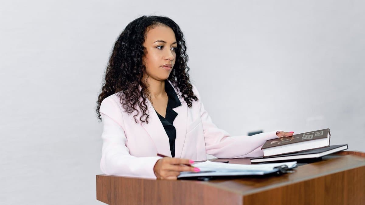 A professional black woman lawyer presenting documents at a podium with books.