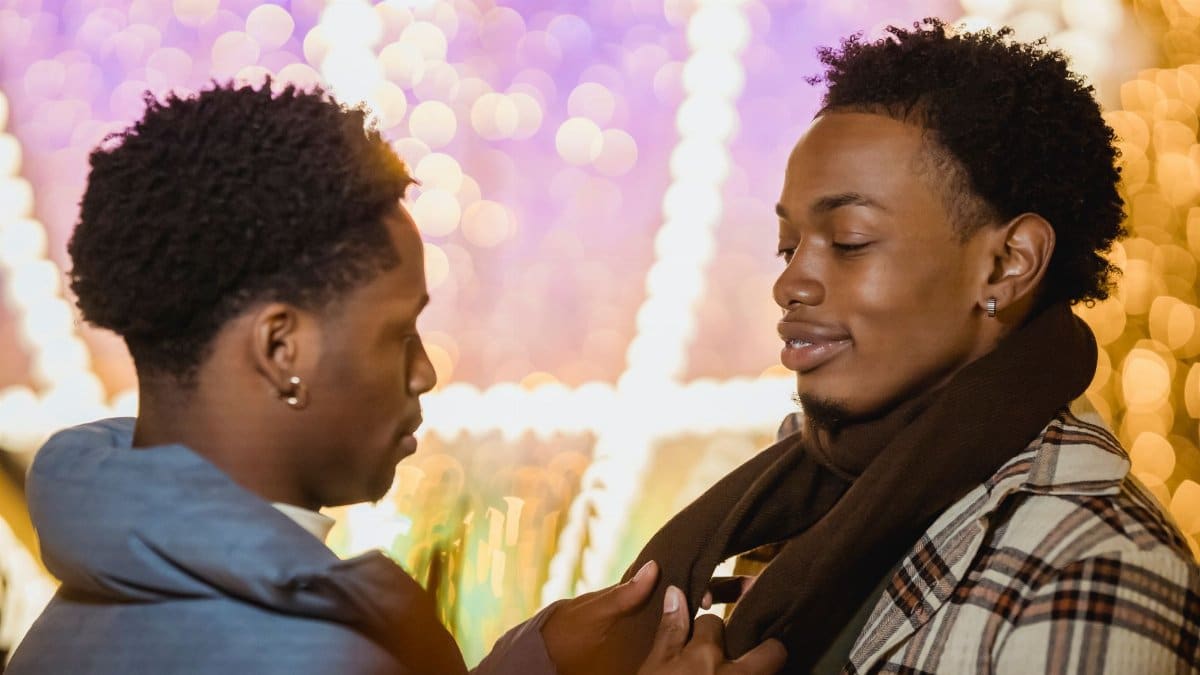 Side view of African American gays looking at each other on blurred background of glowing lights