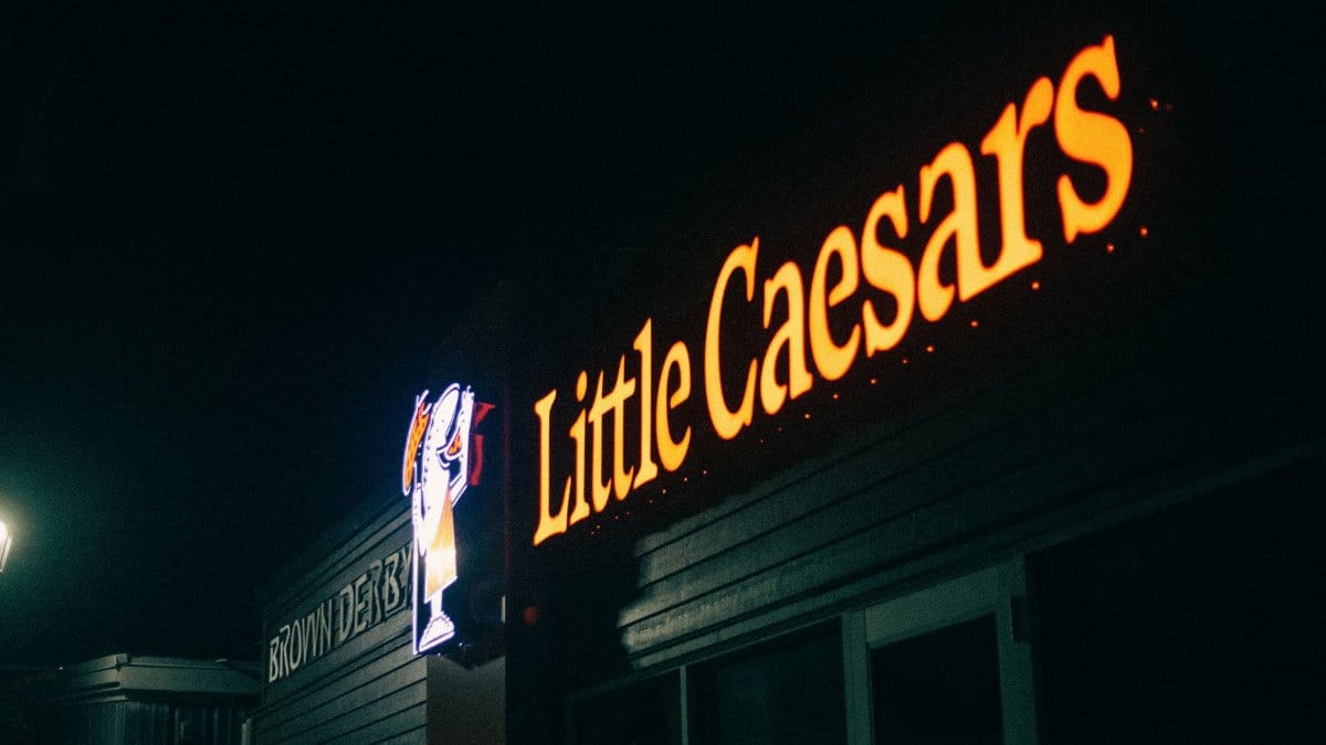 A dimly lit image of a Little Caesars restaurant sign glowing in the night.