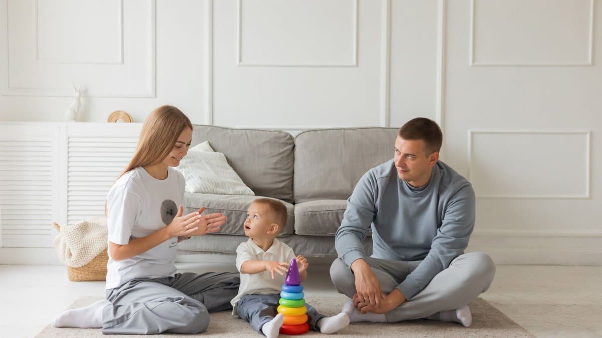Parents playing with their toddler and a colorful toy at home, fostering family bonding.
