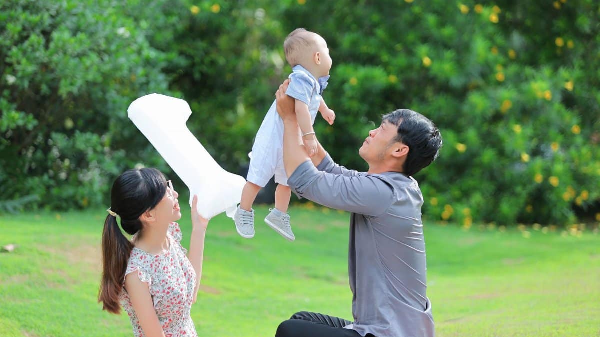 A joyful moment of a family enjoying a picnic outdoors, with parents holding their baby lovingly.