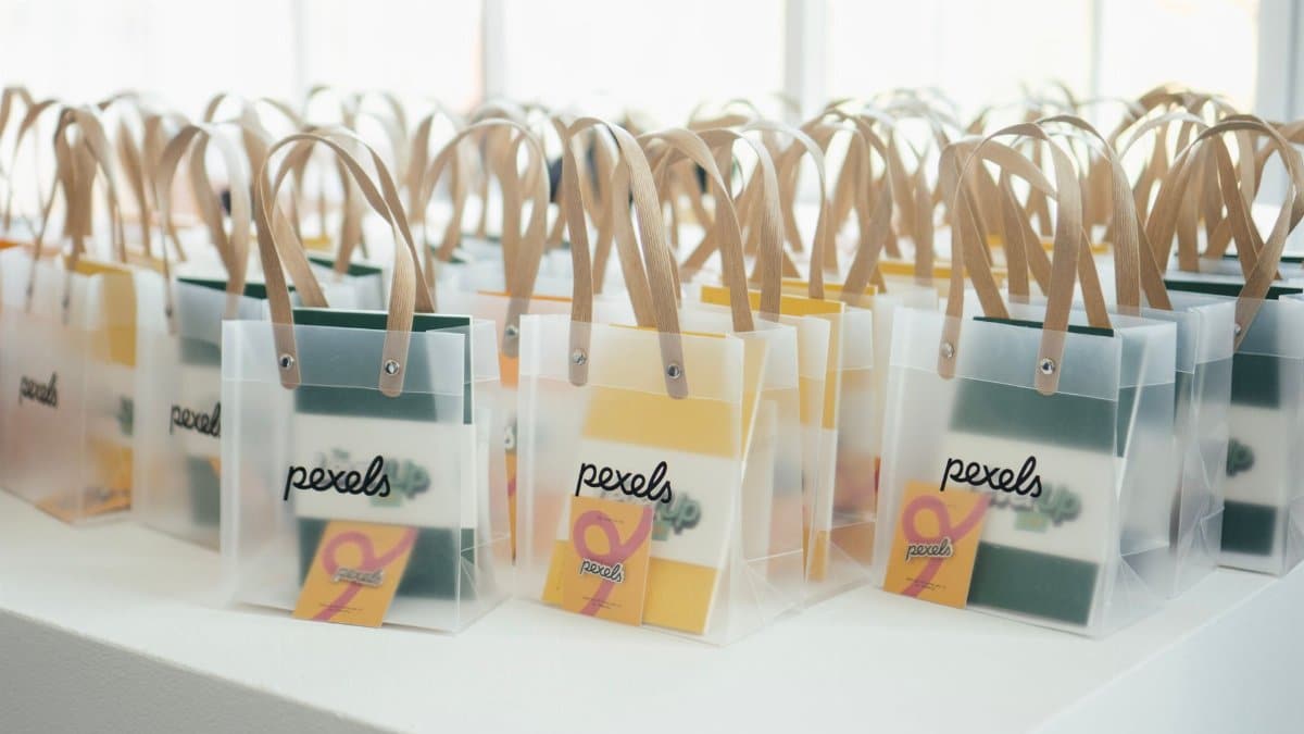 Rows of stylish gift bags with transparent design and wooden handles, ready for an event.