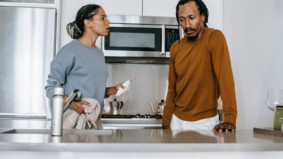 African American guy and lady in casual clothes standing and arguing in kitchen in daytime