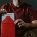 An elderly man opening a red envelope containing a Valentine's Day card, symbolizing love and connection.