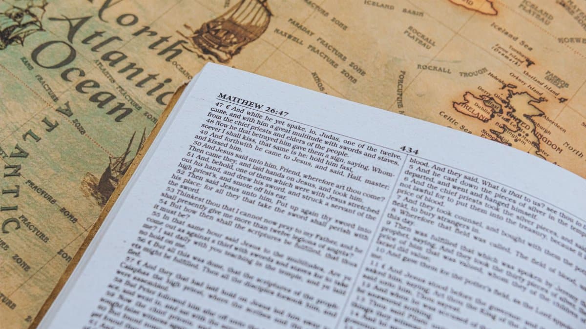 Open Bible with text from Matthew 26:47 on vintage map of North Atlantic Ocean.