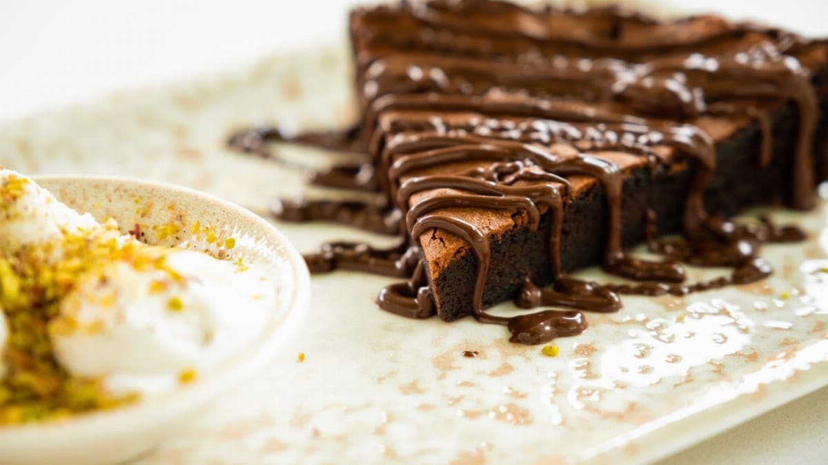 Close-up of a rich chocolate brownie drizzled with chocolate sauce and served with vanilla ice cream.