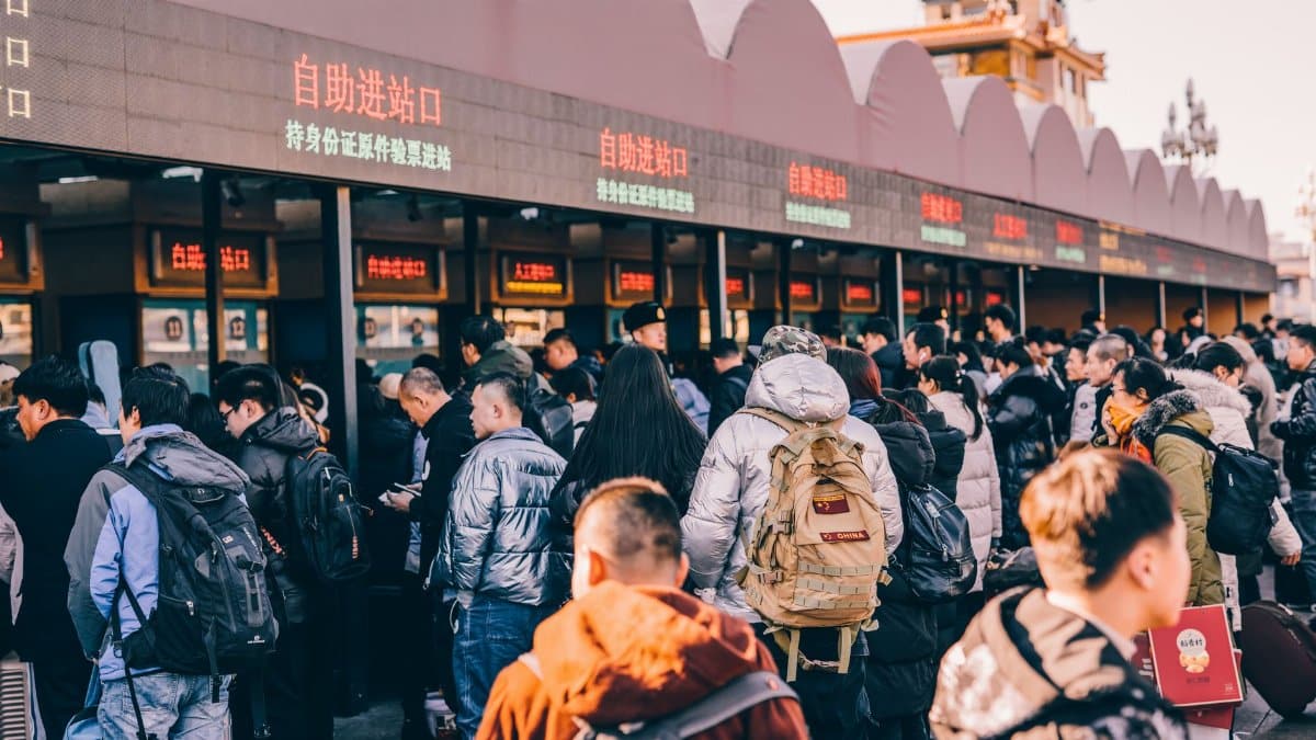 A crowd of people waiting in line at a ticket station in Beijing, China, showcasing modern urban life.