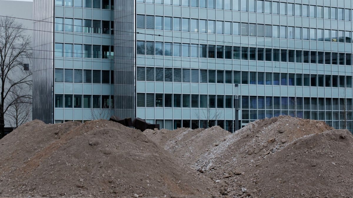 A construction site with dirt piles in front of a modern office building in Düsseldorf, Germany.