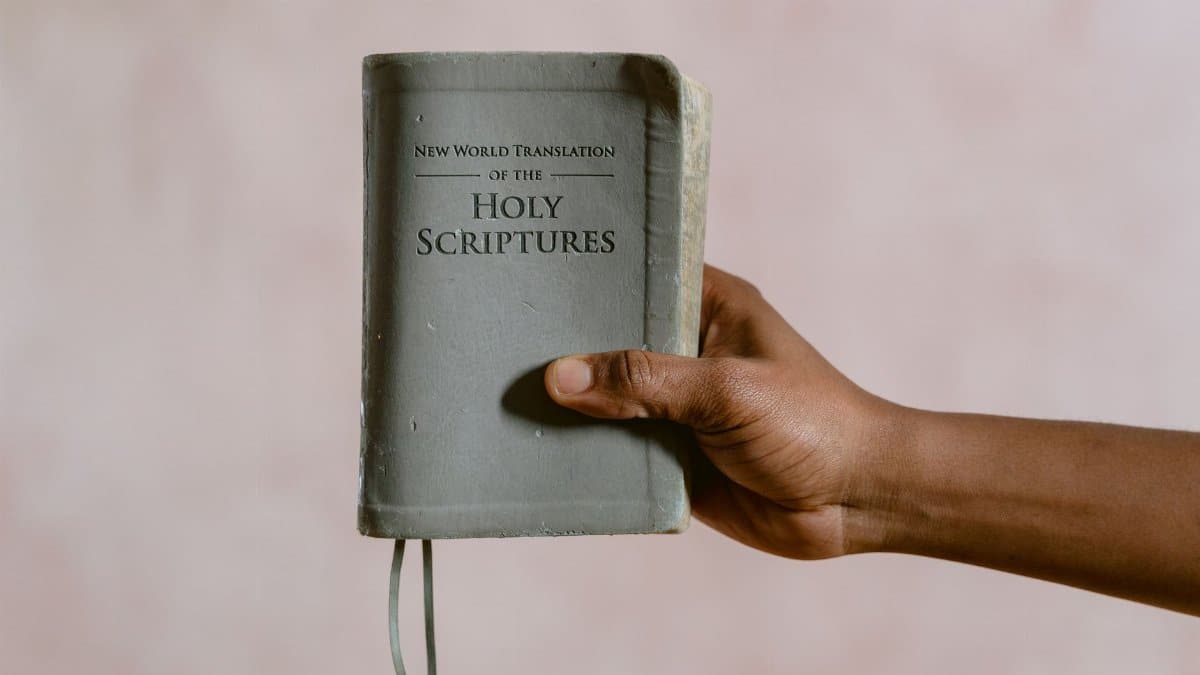 Close-up image of a hand holding the New World Translation of the Holy Scriptures book.
