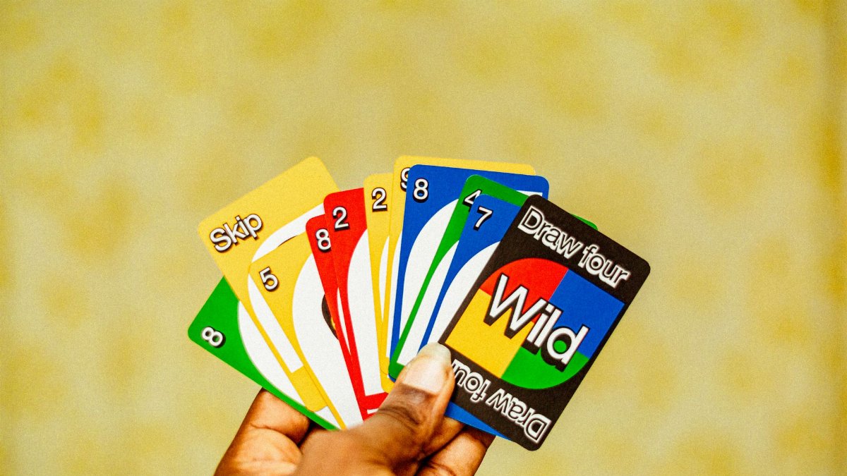 A close-up of a hand holding Uno cards with vibrant colors and strategic game elements.