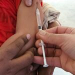 A child getting a vaccination shot administered by a healthcare professional indoors.