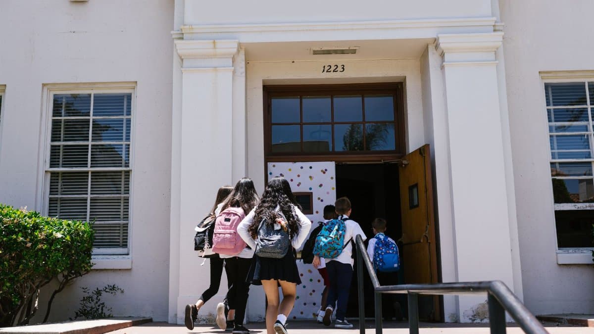 Group of students with backpacks entering a school building. Perfect for back-to-school themes.