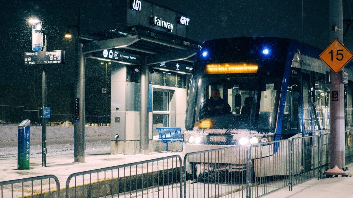 A snowy night at Fairway Station in Kitchener, Ontario with a light rail transit arriving.