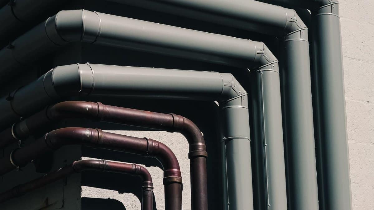 Close-up of industrial pipes forming a pattern on a building's exterior wall, shot outdoors.