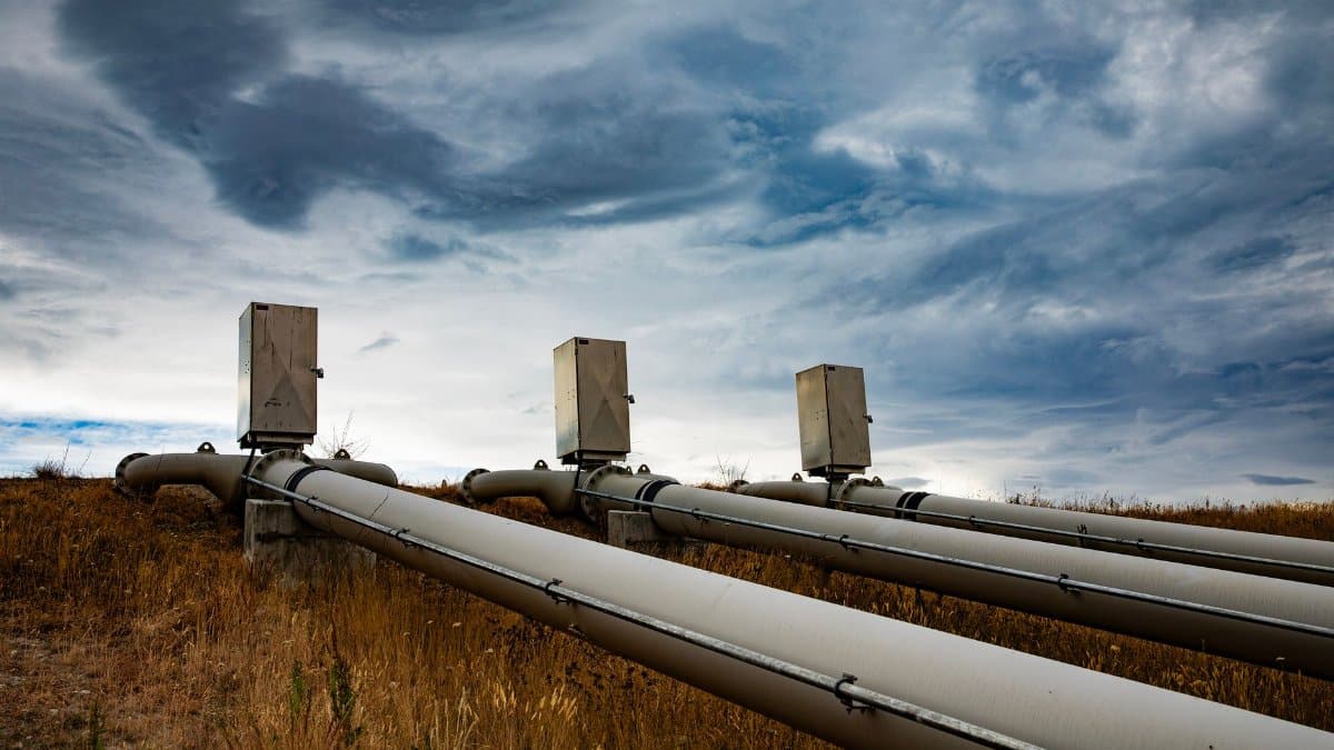 A series of large industrial pipes under a dramatic cloudy sky in New Zealand.