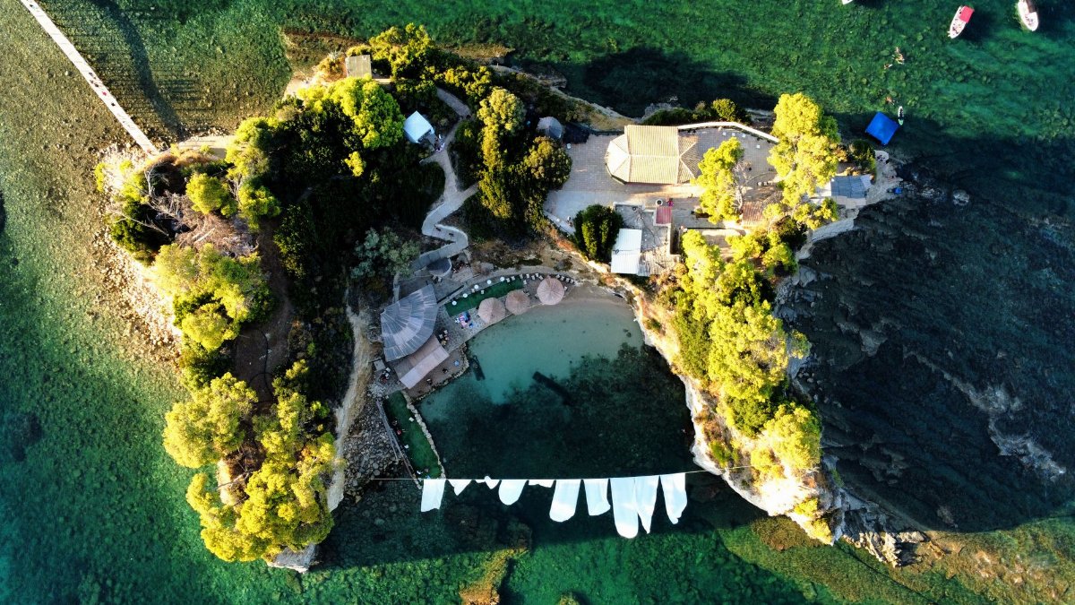 A stunning aerial view of a secluded beach resort in Zakynthos, Greece, surrounded by lush greenery and crystal-clear waters.