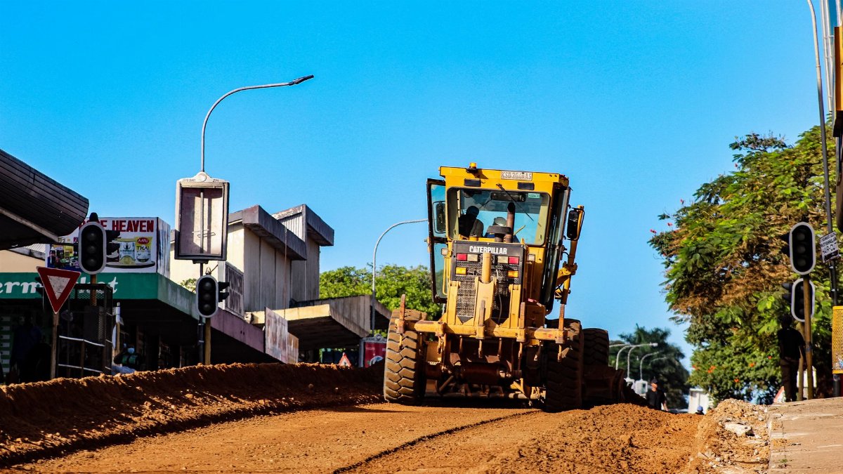 A road construction vehicle working on a street in Manzini with clear blue skies overhead.