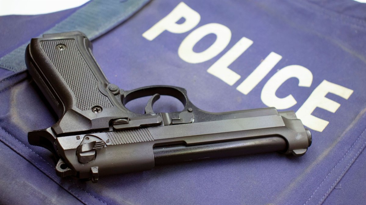 A black pistol resting on a police vest, highlighting law enforcement gear.