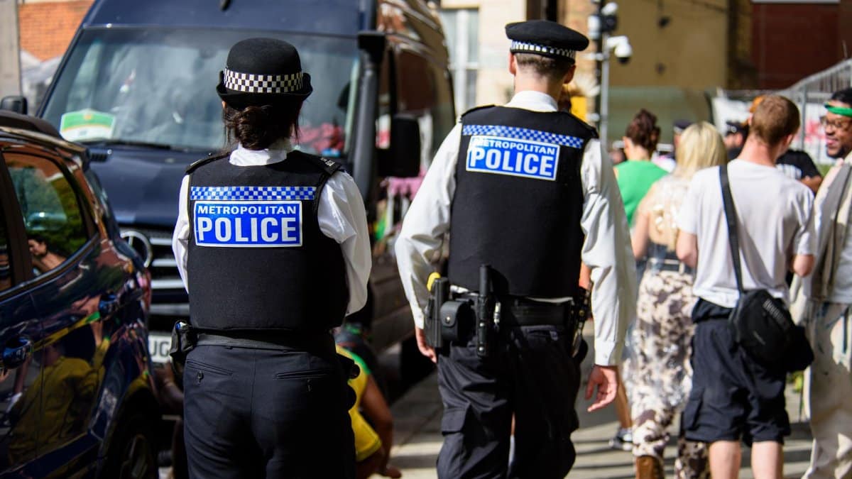 Two Metropolitan Police officers on patrol during a city event in daylight.