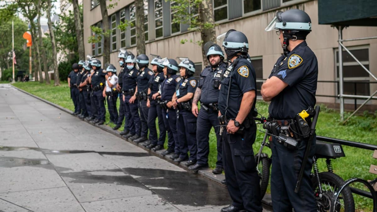 Police officers standing in line outside a building on a city sidewalk.