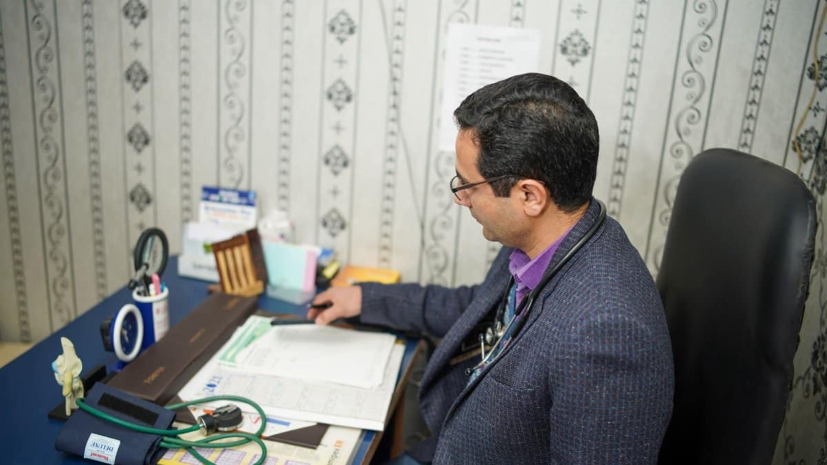 Doctor reviewing medical documents at desk in clinic office.