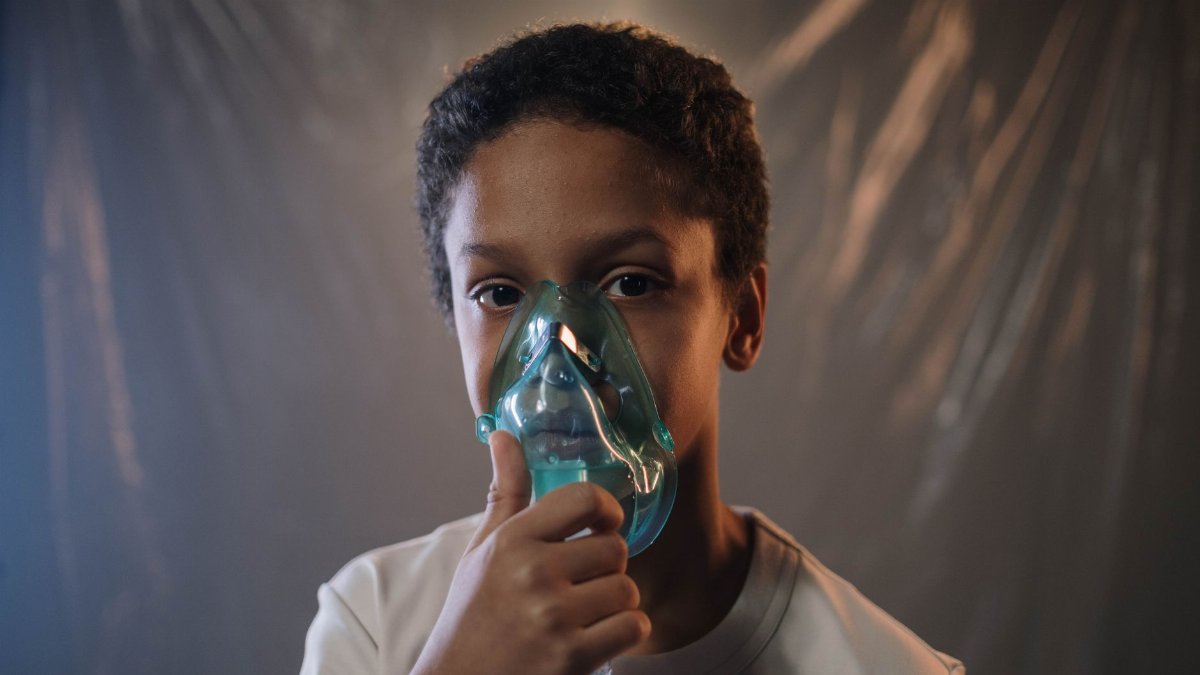 Portrait of a child using an oxygen mask indoors, highlighting health care needs.