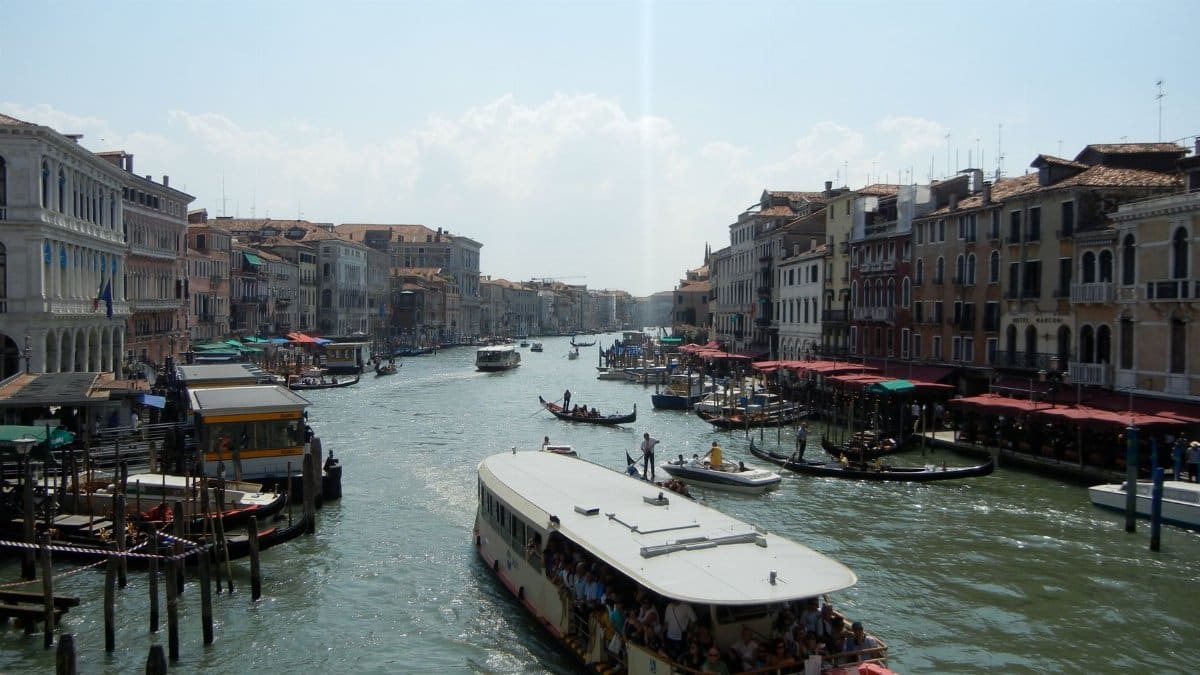 Explore Venice's Grand Canal with boats and historic buildings along the water.
