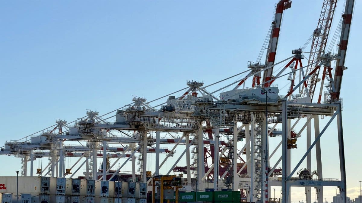 A view of shipping containers and cranes at a bustling port in Australia under clear skies.